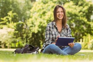 Smiling student sitting and using tablet pc photo