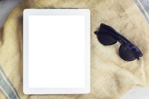 tableta digital en blanco con gafas de sol sobre una toalla, simulacro foto
