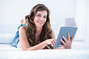 Happy woman using her tablet pc smiling at camera