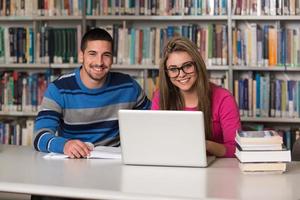 jóvenes estudiantes usando su computadora portátil en una biblioteca foto