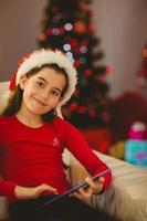 Festive little girl using tablet pc on couch