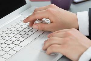 Close-up of woman's hands typing at laptop photo