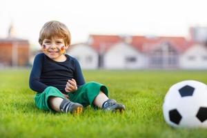 Blond boy of 4 playing soccer with football onl field photo
