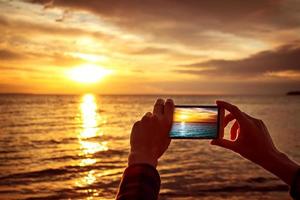 hands holding mobile phone at sunset photo
