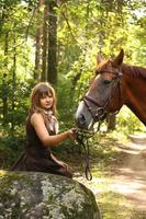 Hermosa niña y retrato de caballo marrón en bosque misterioso foto