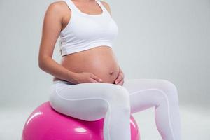 mujer embarazada sentada en una pelota de fitness