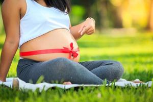Beautiful pregnant asian woman relaxing in the park photo