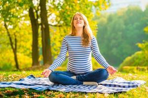 Pregnant woman in a lotus position performs breathing exercises photo