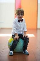Little student at school sitting on globe photo