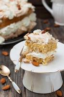 cake with meringue, whipped cream and almonds on wooden background photo