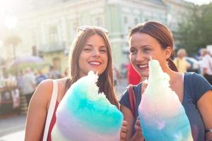young women holding cotton candy and enjoying outdoor