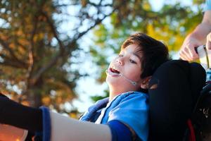 apuesto niño discapacitado en silla de ruedas, disfrutando del atardecer al aire libre foto