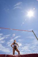 Young female athlete by bar, low angle view (lens flare)