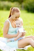 lindo bebé en el parque de verano con la madre en el césped. foto
