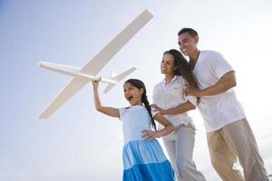 Familia hispana y niña divirtiéndose con avión de juguete foto