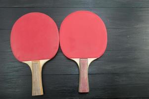Two red table tennis rackets on dark background