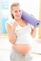 Pregnant woman holding yoga mat