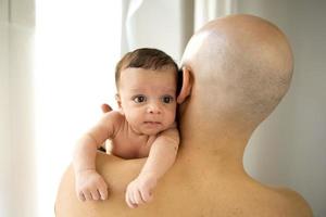 bebé recién nacido llorando sobre el hombro de su padre foto