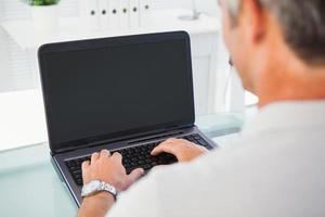 Man with grey hair typing on laptop