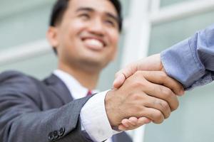 Asian businessman making handshake with smiling face photo