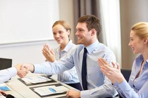 smiling business team shaking hands in office