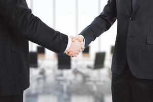 Businessmen shake their hands in conference room