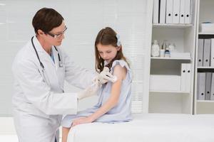 doctor haciendo inyección a una niña foto