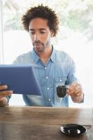 casual hombre tomando café mientras usa la tableta foto