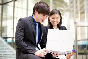 Young female and male Asian business executive using laptop