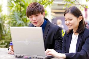 Young female and male Asian business executive using laptop