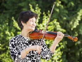 Senior Asian Woman Playing Violin outdoors