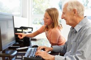 Senior man and granddaughter using computer photo