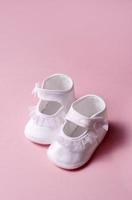 Girl's satin newborn baby shoes on a pink background photo