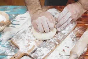 Baker kneading pizza dough photo