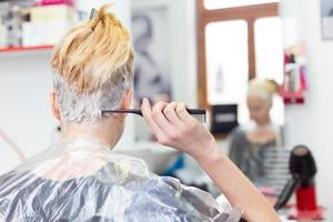 Hairdresser salon. Woman during hair dye. photo