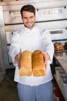 Smiling baker showing loaves of bread