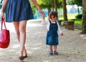 Happy young mother and adorable toddler girl walking through sum photo