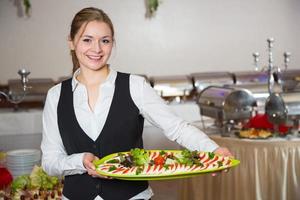Catering service employee posing with tray for buffett photo