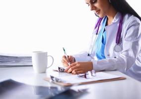 Doctora sentada en el escritorio con papel y trabajando