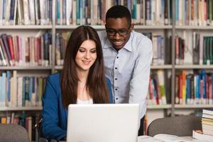 pareja de estudiantes con laptop en biblioteca foto
