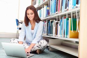 Estudiante universitario femenino que estudia en biblioteca con laptop foto