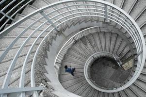 Man in a blue shirt walking down a spiral staircase