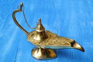 Magical genie lamp isolated on a blue wooden background photo
