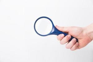 Man's hand, holding classic styled magnifying glass, closeup