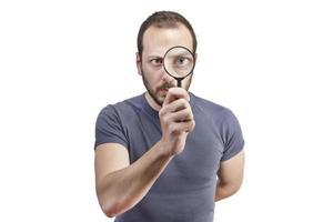 Astonished man looking through a magnifying glass photo