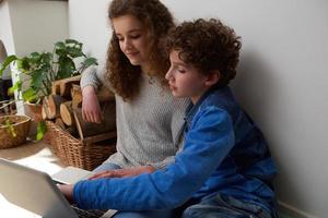 Cute boy and girl using laptop together at home photo