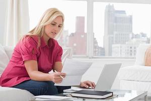 una mujer usando una laptop y leyendo documentos