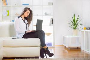 Attractive young woman using her laptop at home photo