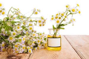 Alternative medicine concept - bottle with camomile on wooden ta photo