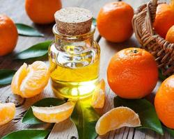 Bottle of essential citrus oil and ripe tangerines with leaves photo